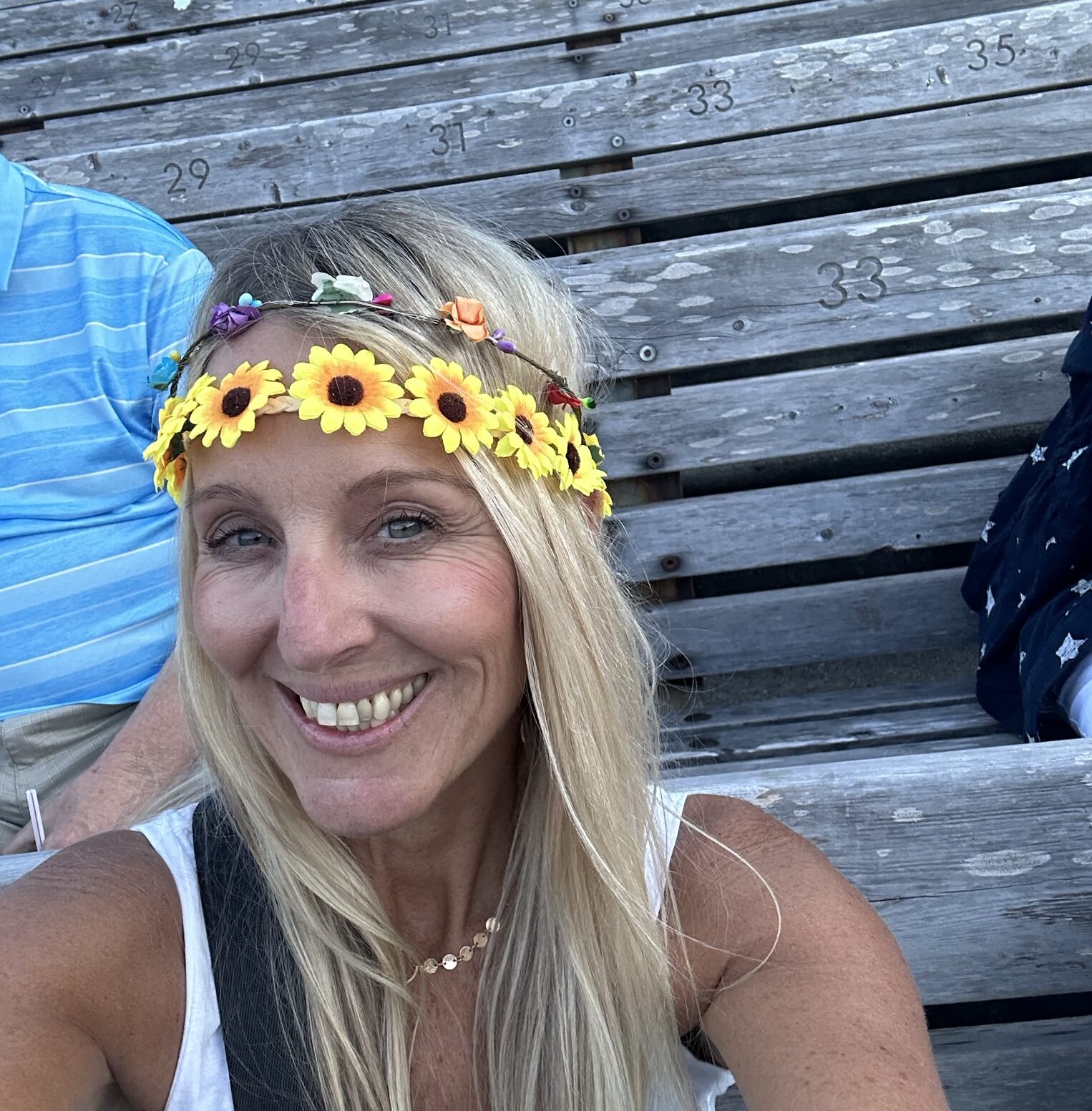 A woman with long blonde hair smiles while wearing a flowery headband.