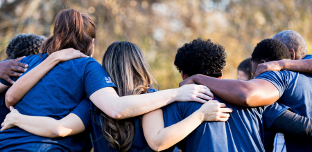 Group of people standing with their arms around each other
