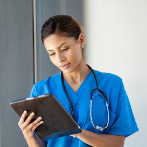 Woman in scrubs holding a clipboard and wearing a stethoscope