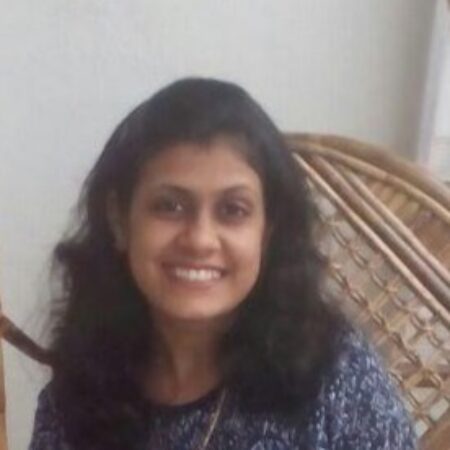 A woman with wavy black hair smiles at the camera