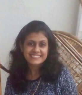 A woman with wavy black hair smiles at the camera
