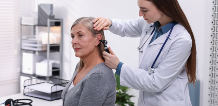 A woman is getting her ear examined by a doctor to test her hearing